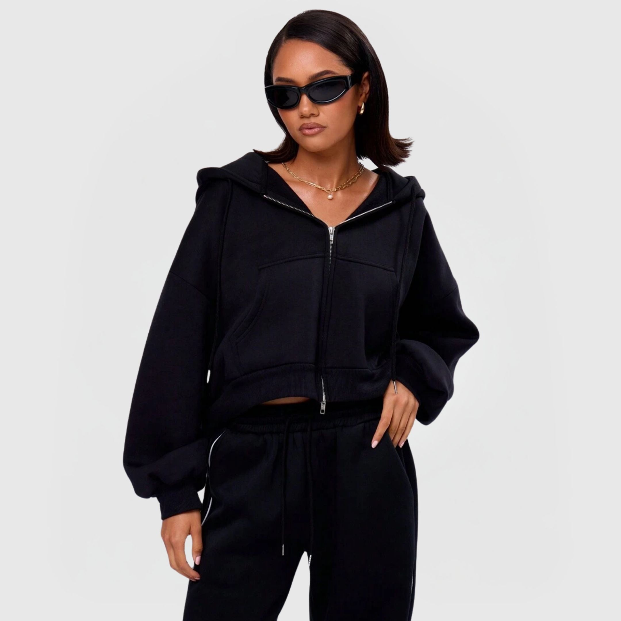 Woman wearing a black Comfort Zip Hoodie – Black with full zip, drawstring hood, and ribbed cuffs in a minimal style.