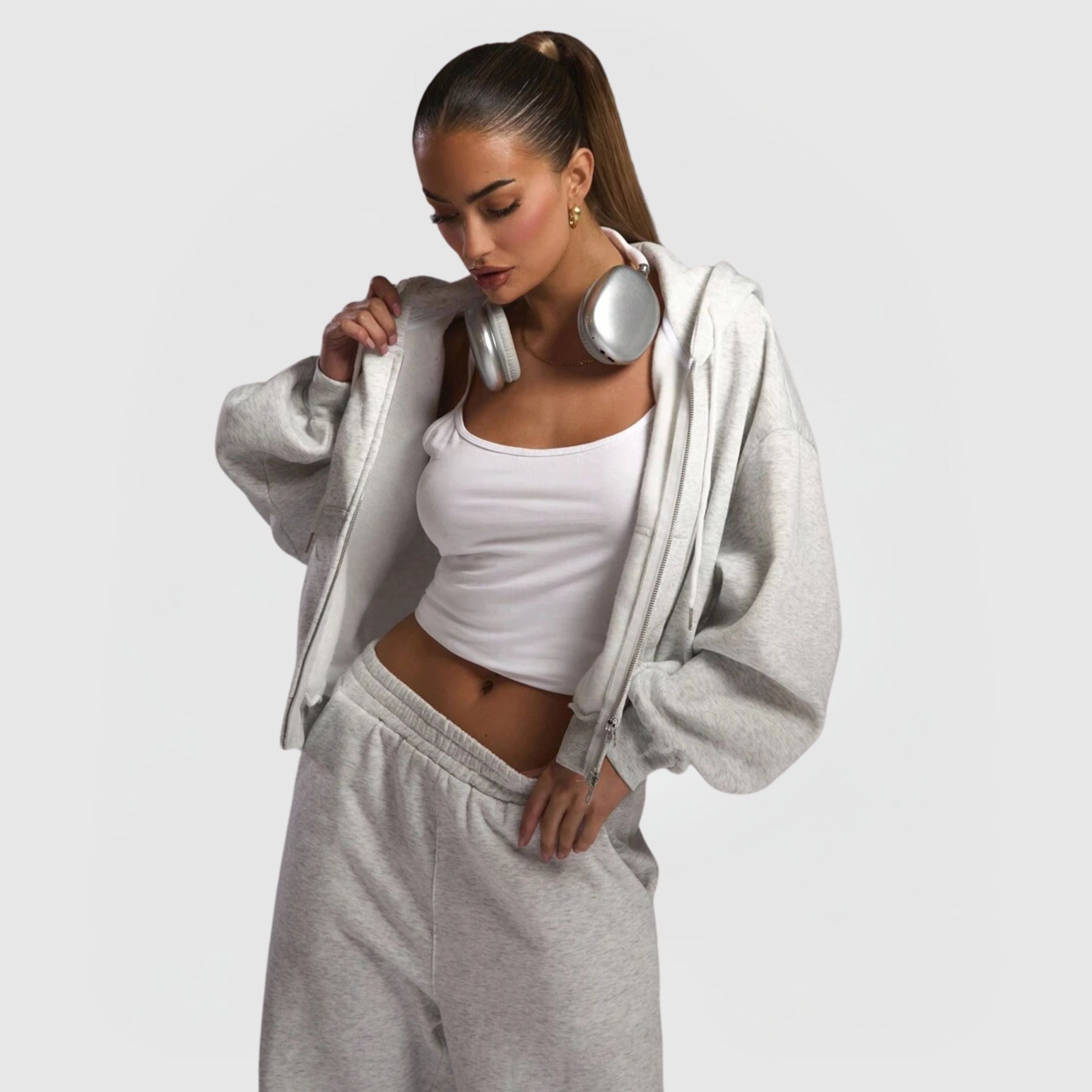 Woman wearing Comfort Zip Hoodie – Grey with matching sweatpants and headphones around neck against plain background