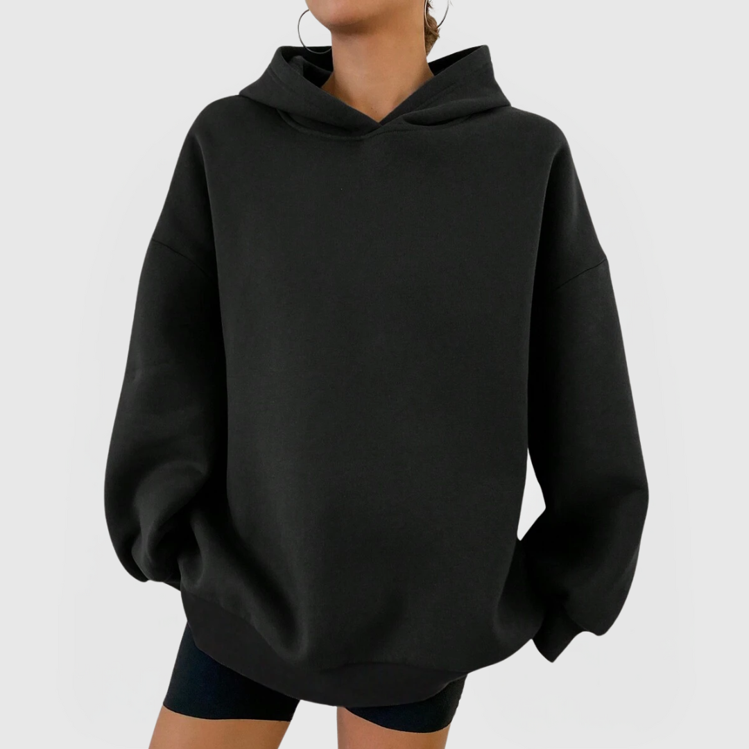 Model wearing an oversized black hoodie with dropped shoulders and relaxed fit, Oversized Essential Hoodie – Black.