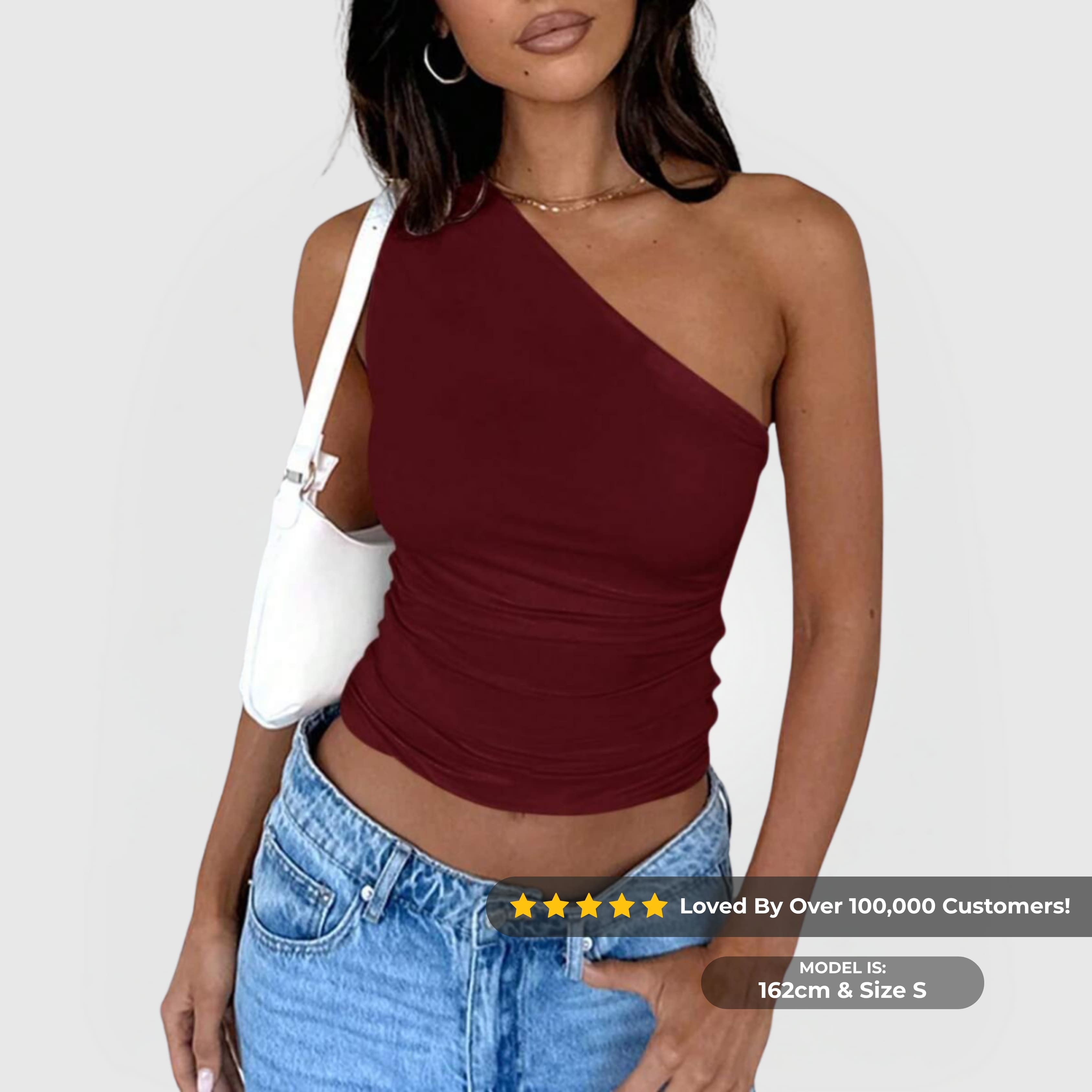 Woman wearing a burgundy One-Shoulder Ruched Top paired with blue jeans and a white shoulder bag