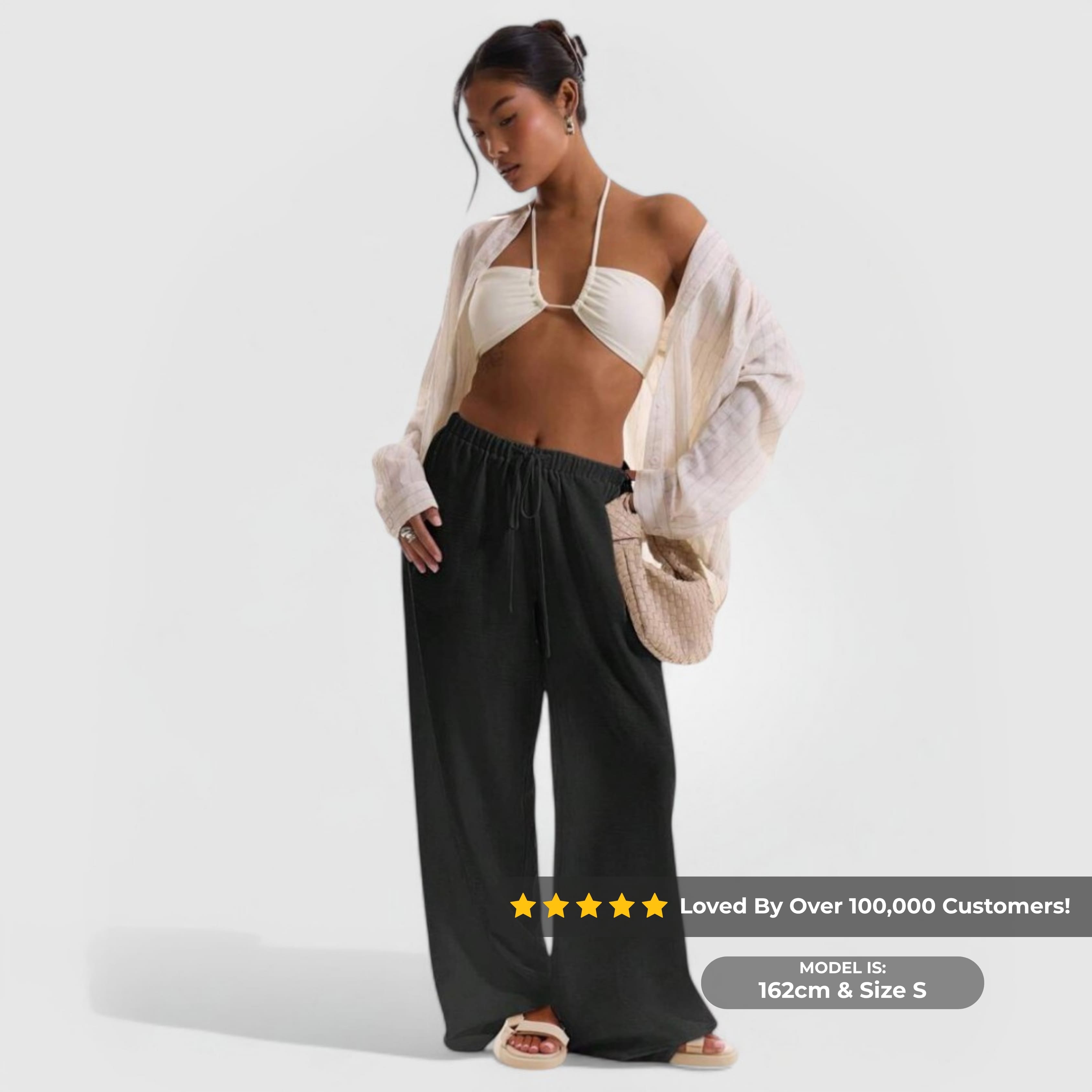 Model wearing Relaxed Linen Pants - Black with a white bikini top and light open shirt against a plain background